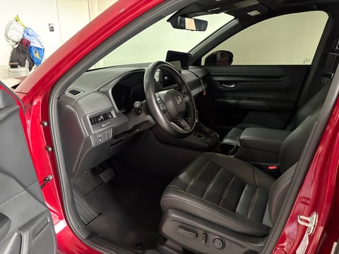 Interior of a red car with black leather seats, steering wheel, dashboard, and open driver-side door