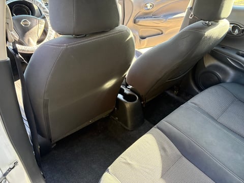 Interior view of a vehicle showing black leather front seats, steering wheel, and beige carpeted floor with center console
