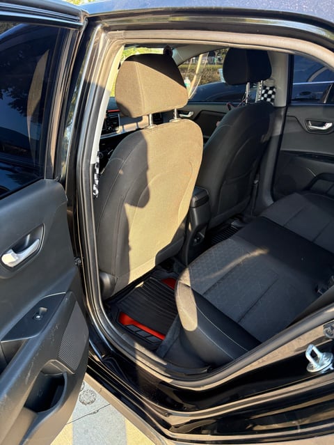 Car interior with tan and black seat covers installed on front and rear seats, door open showing upholstery