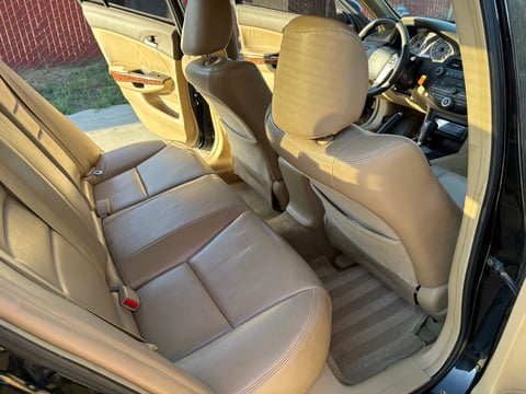 Interior of yellow and black car showing beige leather seats, steering wheel, and dashboard view from open driver side door