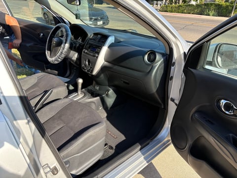 Interior view of compact car with steering wheel, dashboard, gray fabric seats, and open drivers side door