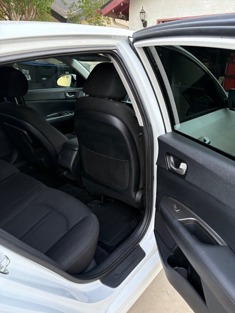 White car with open rear door showing black interior seats and door panel