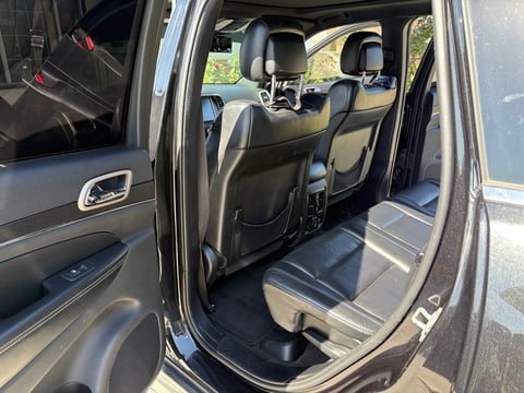 Interior view of open SUV door showing black leather seats and dashboard, exterior daylight visible
