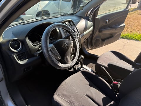 Interior of a compact car showing steering wheel, dashboard, and front seats with driver side door open