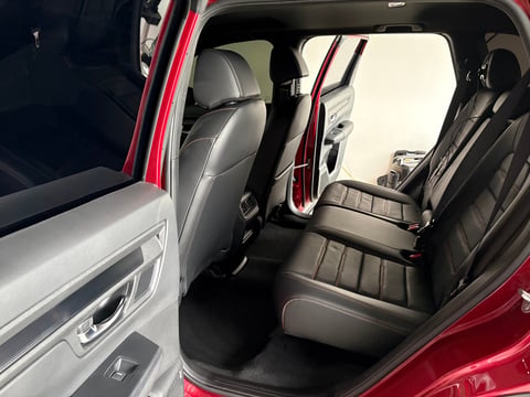 Interior view of a red car with open doors showing gray and black leather seats and dashboard
